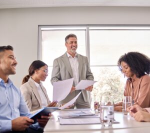 Happy senior executive leading business team meeting in office board room.