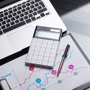 Modern calculator is on a laptop and on a sheet with a graph